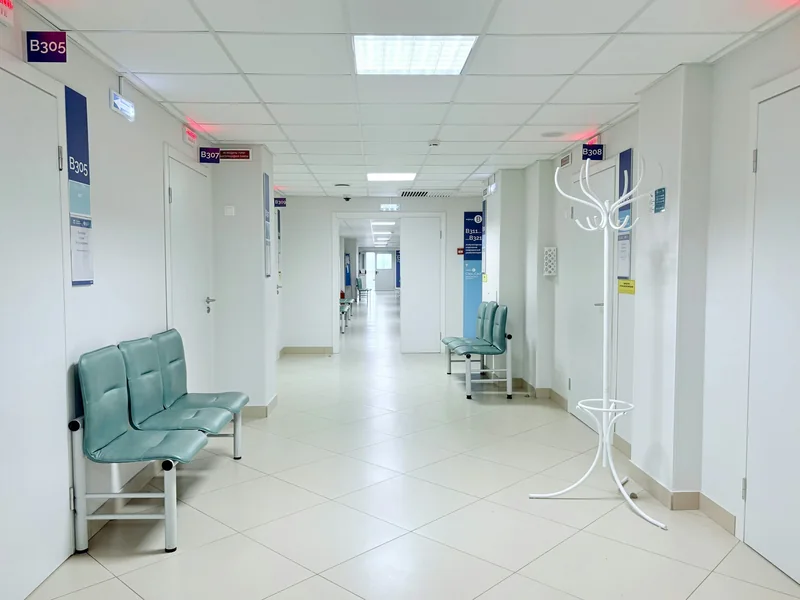 A bright, empty healthcare corridor with seating for visitors.
