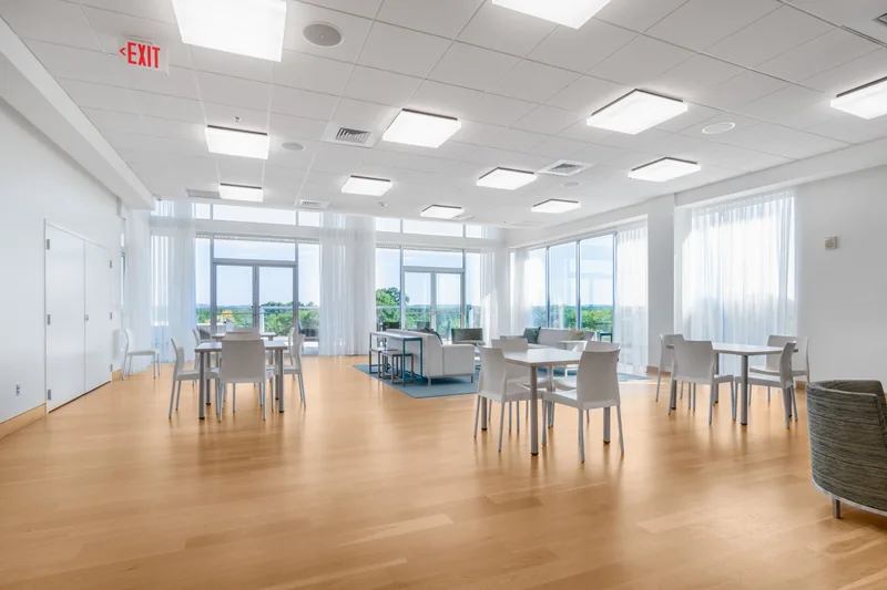 A bright shared lounge with tables, chairs and comfortable seating.