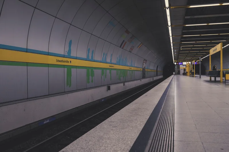 A quiet urban rail platform with seating and overhead lighting.